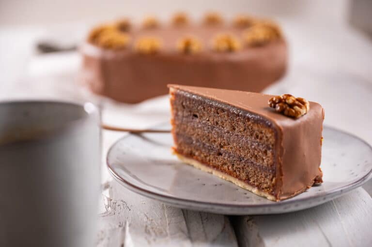 Gmundnertorte Stück und im Hintergrund verschwommen eine ganze Torte